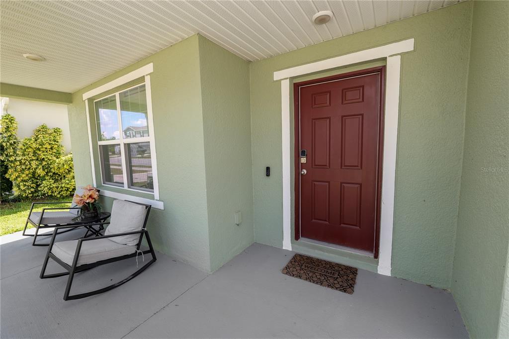A covered front porch features a red door, a window, and two rocking chairs — 871 FILLMORE COURT, DAVENPORT, FL