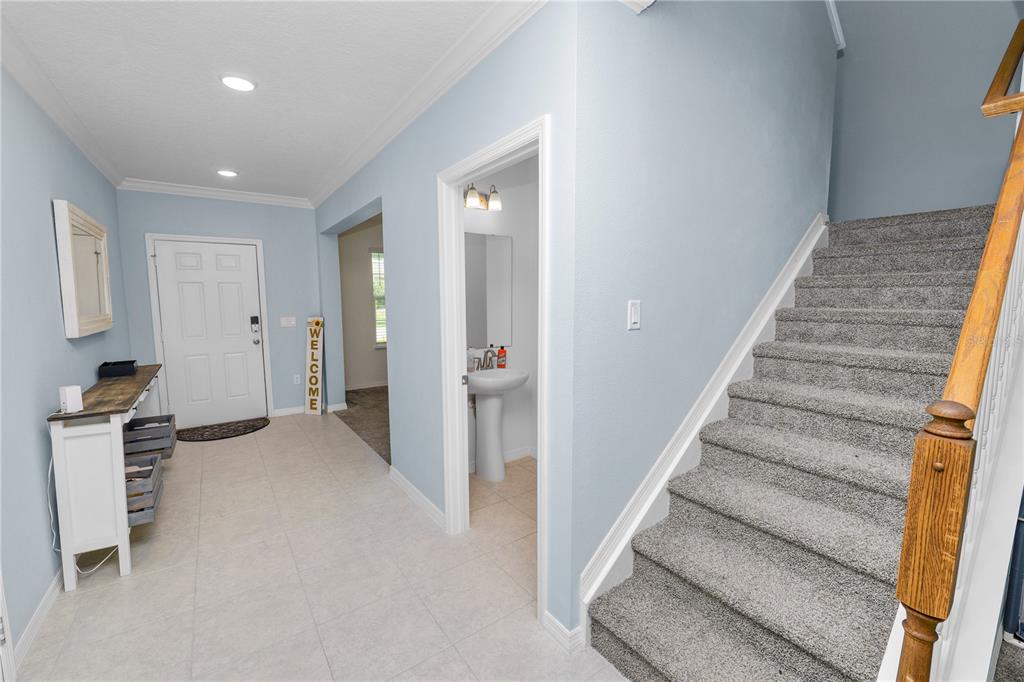 An entryway features light blue walls, tile flooring, a carpeted staircase, and a half bathroom — 871 FILLMORE COURT, DAVENPORT, FL