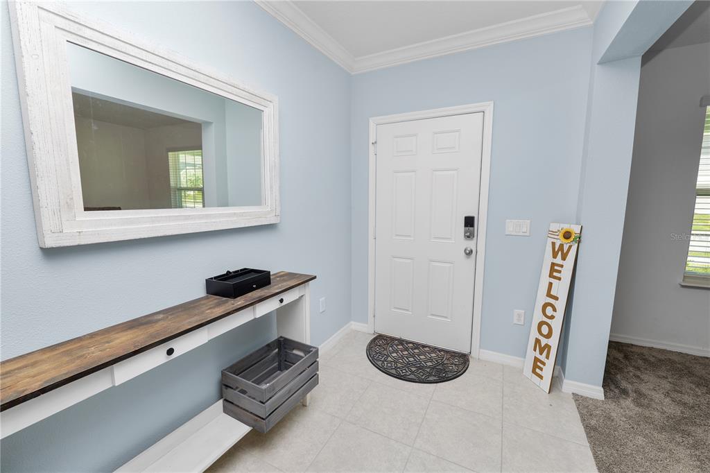 An entryway features light blue walls, a white console table, a mirror, and a welcome sign — 871 FILLMORE COURT, DAVENPORT, FL