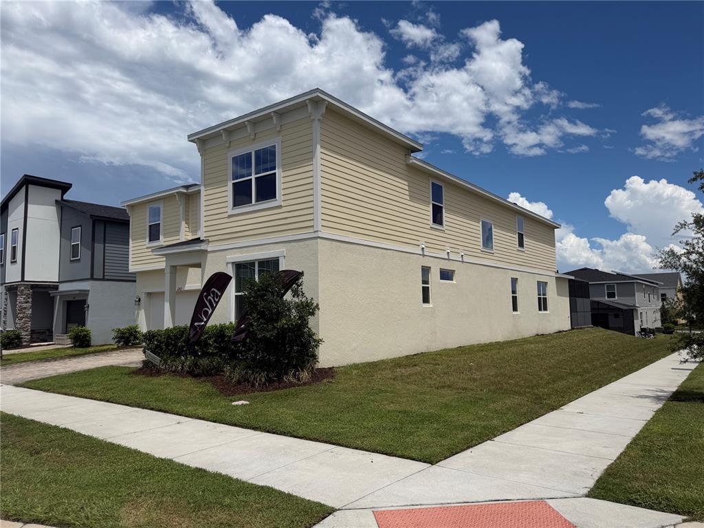 A two-story house with yellow siding and stucco exterior sits on a corner lot — 2303 SEA ROCK ROSE TRAIL, KISSIMMEE, FL