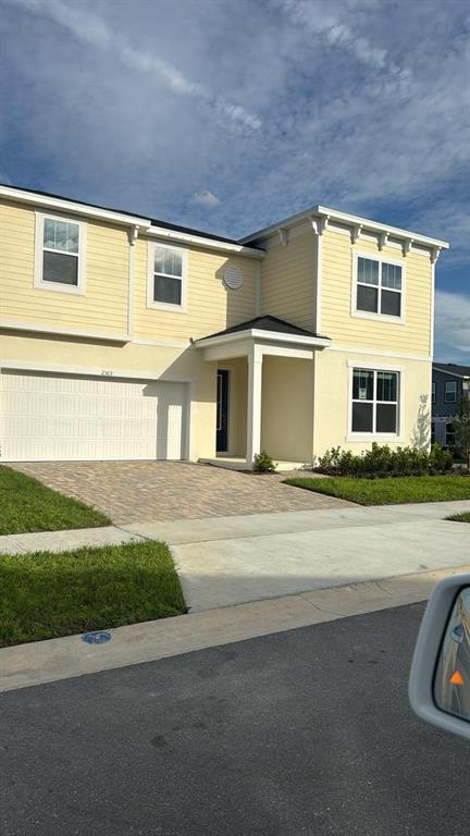 A two-story yellow house with a white garage door and a covered front entryway — 2303 SEA ROCK ROSE TRAIL, KISSIMMEE, FL