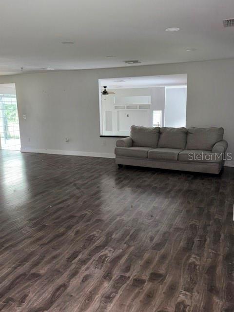 A living room features dark wood-look flooring, a gray sofa, and a large wall opening — 21103 REINDEER ROAD, CHRISTMAS, FL