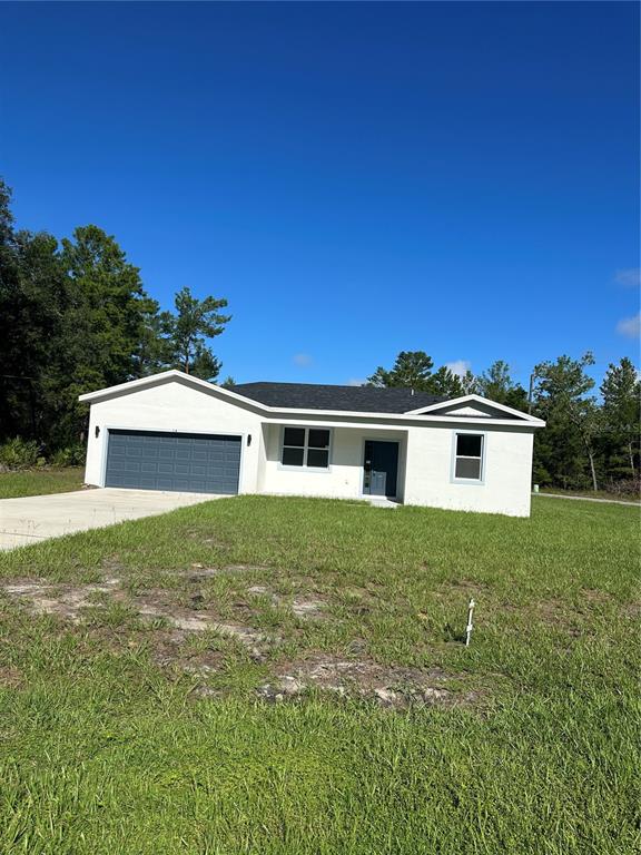 A single-story white stucco house with a gray garage door sits on a grassy lot — 14 FISHER COURT, OCKLAWAHA, FL