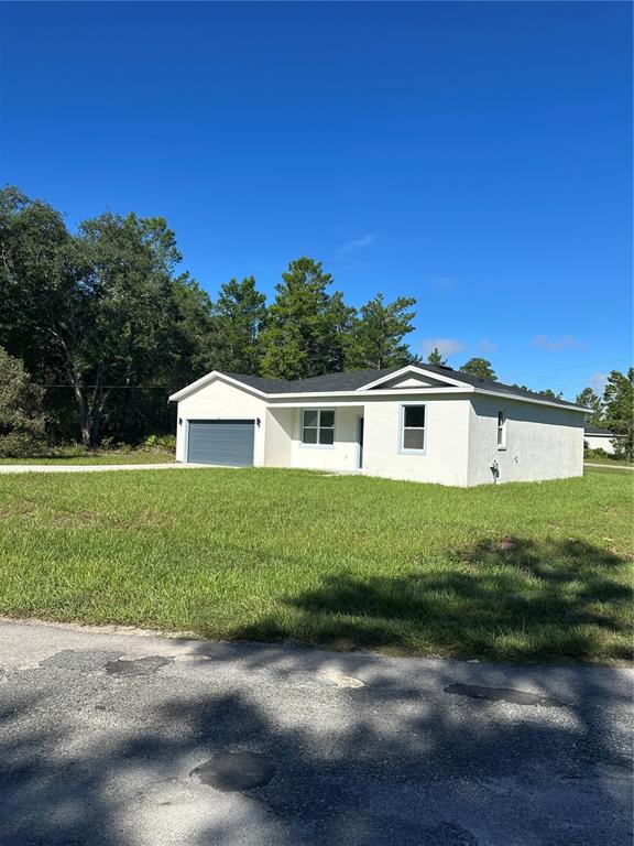 A single-story white house with a garage sits on a grassy lot near a road — 14 FISHER COURT, OCKLAWAHA, FL