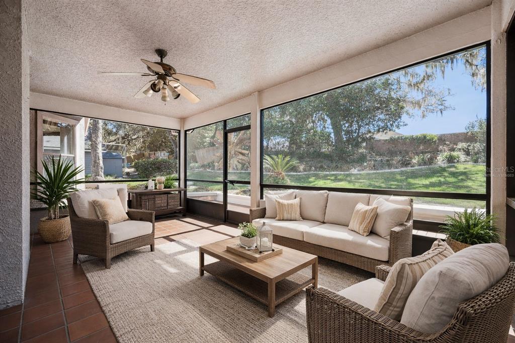 A screened-in patio features wicker furniture, a ceiling fan, and large windows overlooking a yard — 108 OAK VIEW CIRCLE, LAKE MARY, FL