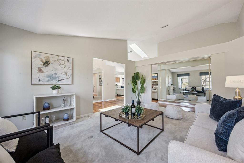 A living room features a vaulted ceiling, a large mirror, a coffee table, and seating — 108 OAK VIEW CIRCLE, LAKE MARY, FL