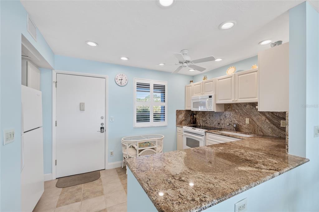 A kitchen features light blue walls, white cabinets, granite countertops, and a white refrigerator — 4310 FALMOUTH DRIVE UNIT 307, LONGBOAT KEY, FL