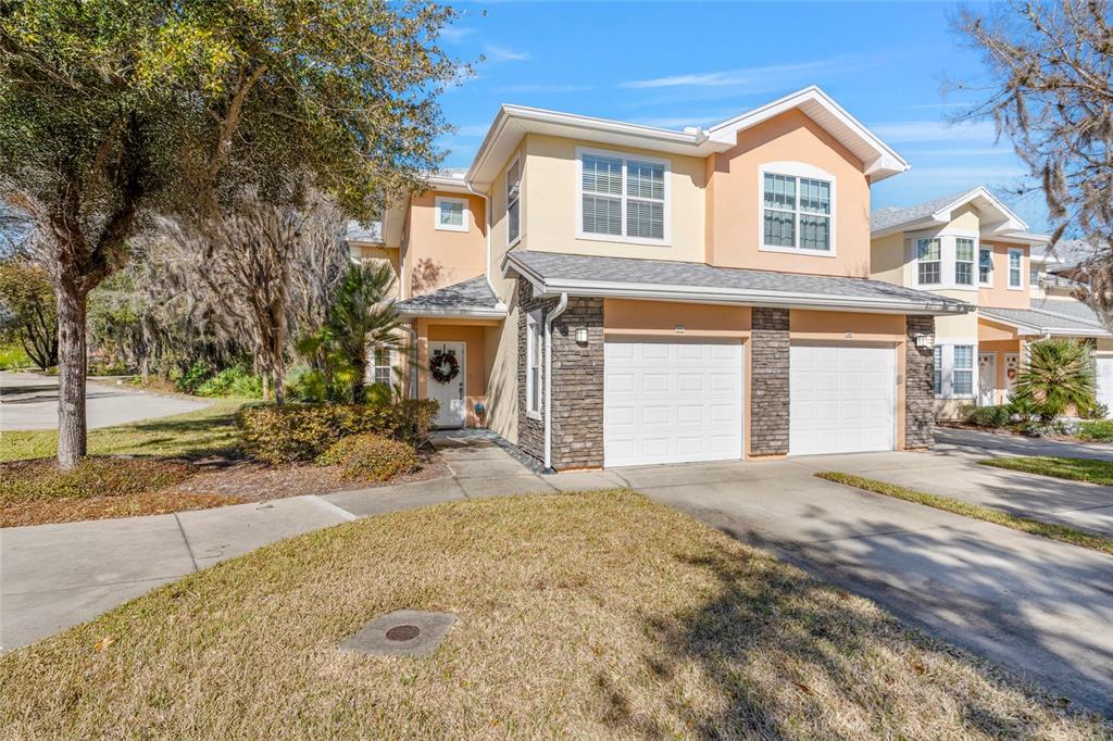 A two-story duplex with a stone-accented facade, two garage doors, and a concrete driveway — 110 MAGNOLIA CROSSING POINT UNIT 1901, ST AUGUSTINE, FL