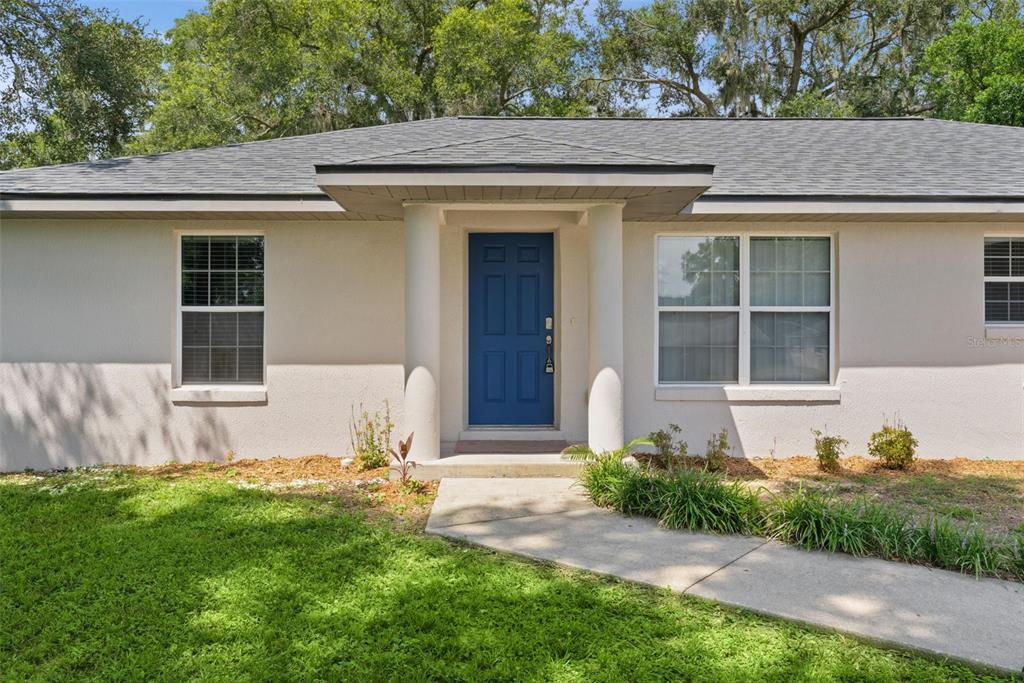 The exterior of a single-story house features a blue front door flanked by two white columns — 36127 PINE TREE STREET, FRUITLAND PARK, FL