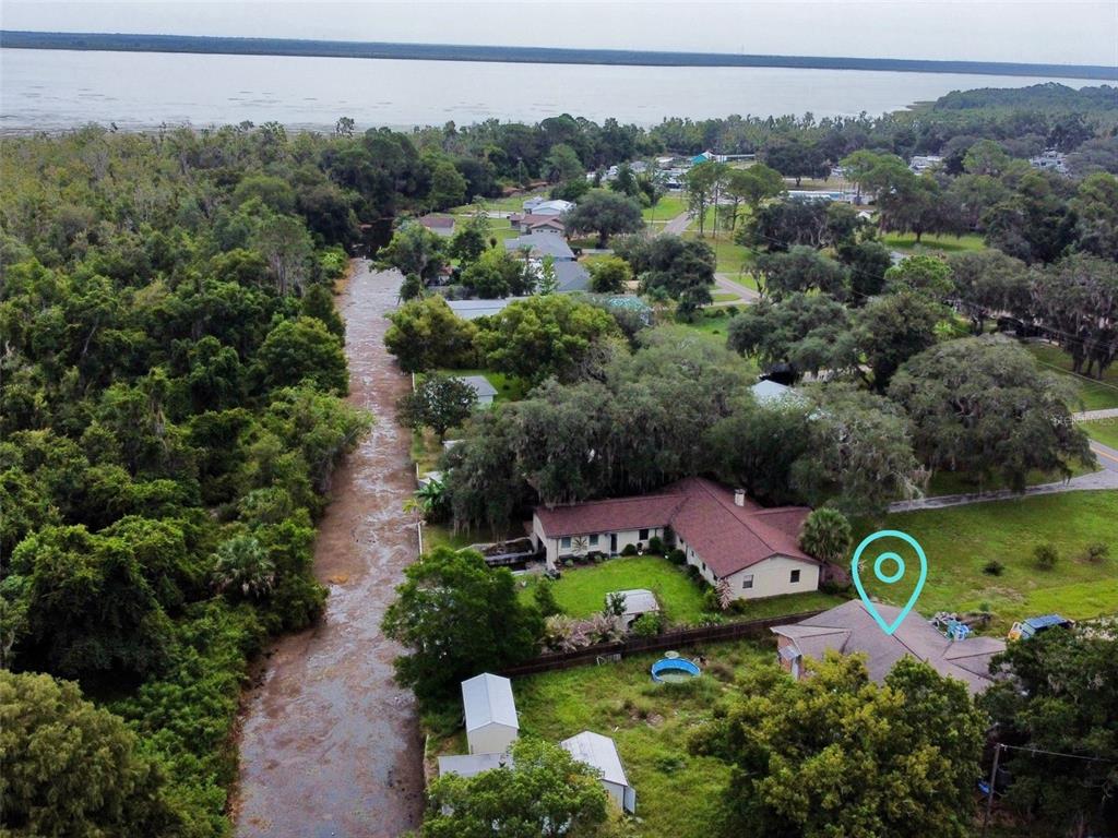An aerial view shows a house with a blue location pin near a wooded creek — 5243 EAGLES NEST ROAD, FRUITLAND PARK, FL