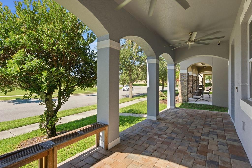 A covered porch with arched columns, stone accents, a ceiling fan, and a brick paver floor — 13786 SUMMER HARBOR COURT, WINDERMERE, FL