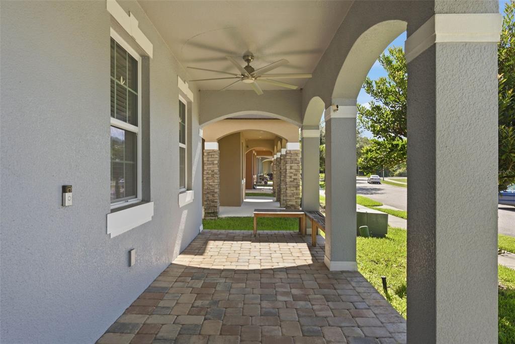 A covered patio with a ceiling fan, stone-look pavers, and arched columns overlooking a street — 13786 SUMMER HARBOR COURT, WINDERMERE, FL