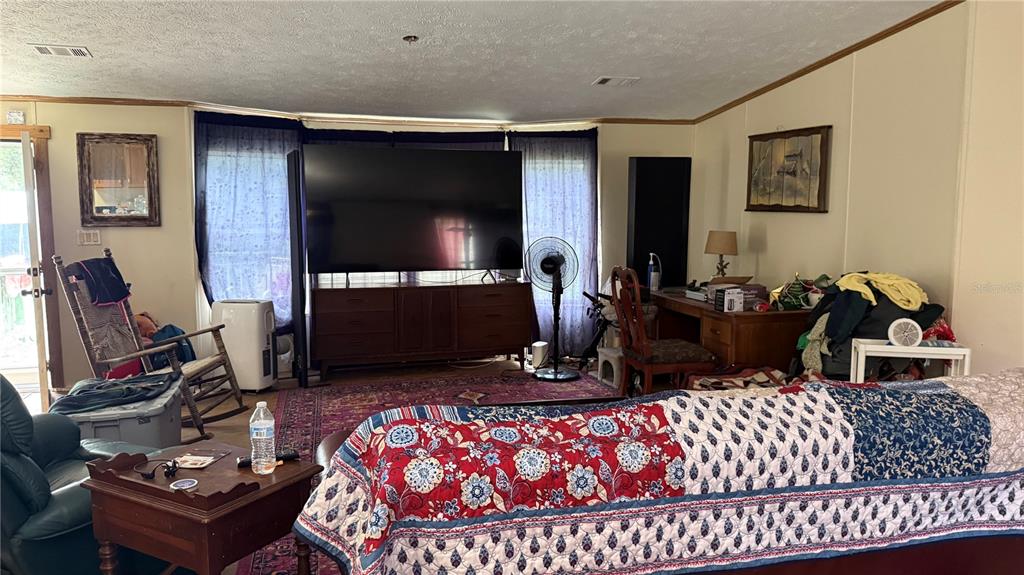 A living room features a large television on a dresser, a patterned sofa, and a desk — 12171 NW 168TH PLACE, REDDICK, FL