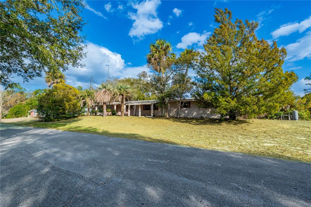 An aerial view shows a house with a metal roof, concrete driveway, and surrounding trees — 15851 NE 15TH STREET, WILLISTON, FL