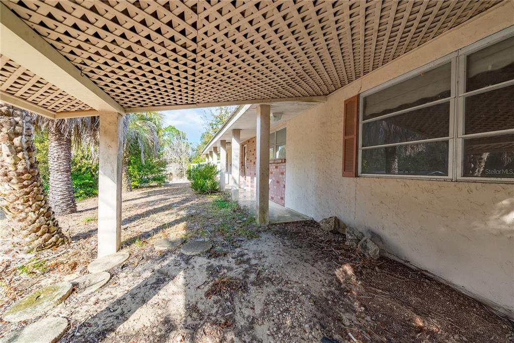 An exterior view of a house with a metal roof, covered porch, and palm trees — 15851 NE 15TH STREET, WILLISTON, FL