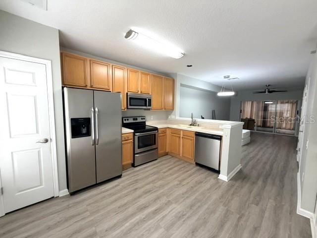 A kitchen features stainless steel appliances, light wood cabinets, and light-colored wood-look flooring — 1178 VINELAND PLACE, LAKE MARY, FL