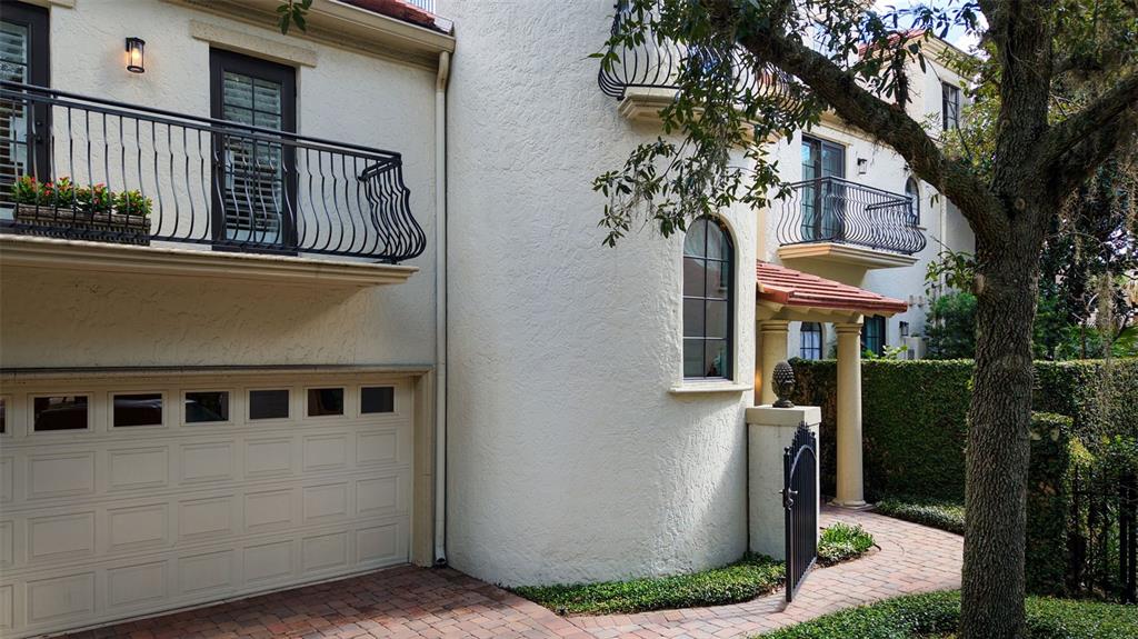 Exterior view of a stucco home with a garage, balconies, and a brick walkway — 1256 S PENNSYLVANIA AVENUE UNIT 9, WINTER PARK, FL