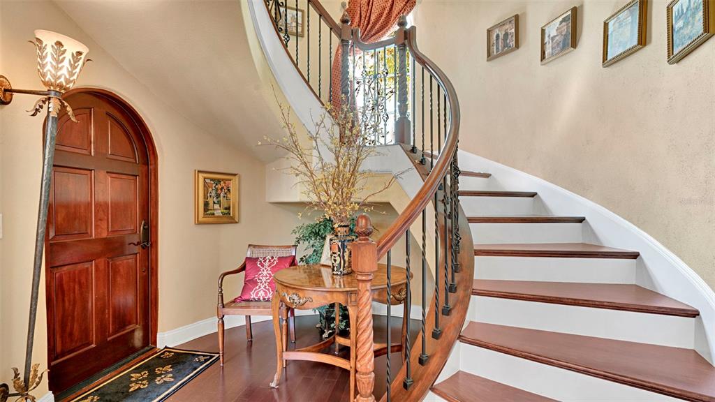 A curved staircase with wooden treads and iron railings stands in a home entryway — 1256 S PENNSYLVANIA AVENUE UNIT 9, WINTER PARK, FL