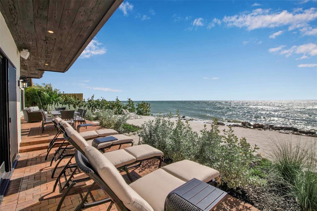 A brick patio features lounge chairs overlooking a sandy beach and the ocean — 121 N CASEY KEY ROAD, OSPREY, FL