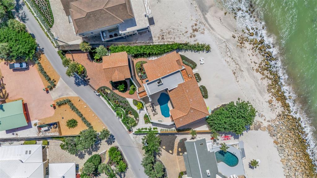 An aerial view shows two white Mediterranean-style houses with terracotta roofs near the ocean — 121 N CASEY KEY ROAD, OSPREY, FL