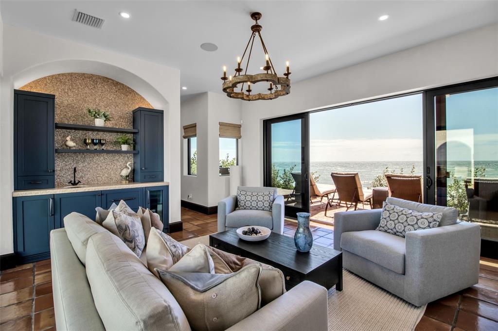 An aerial view shows a beachfront house with a pool, tile roof, and sandy yard — 121 N CASEY KEY ROAD, OSPREY, FL