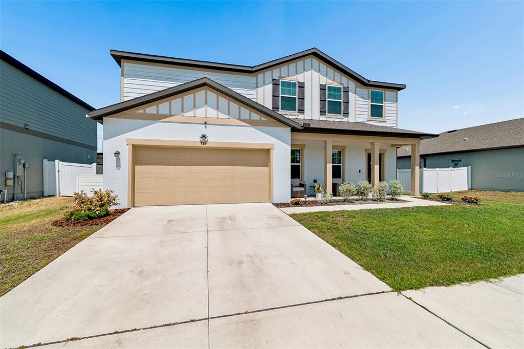 A two-story house with a white stucco facade, tan garage door, and a covered porch — 575 OCEAN SPRAY DRIVE, RUSKIN, FL