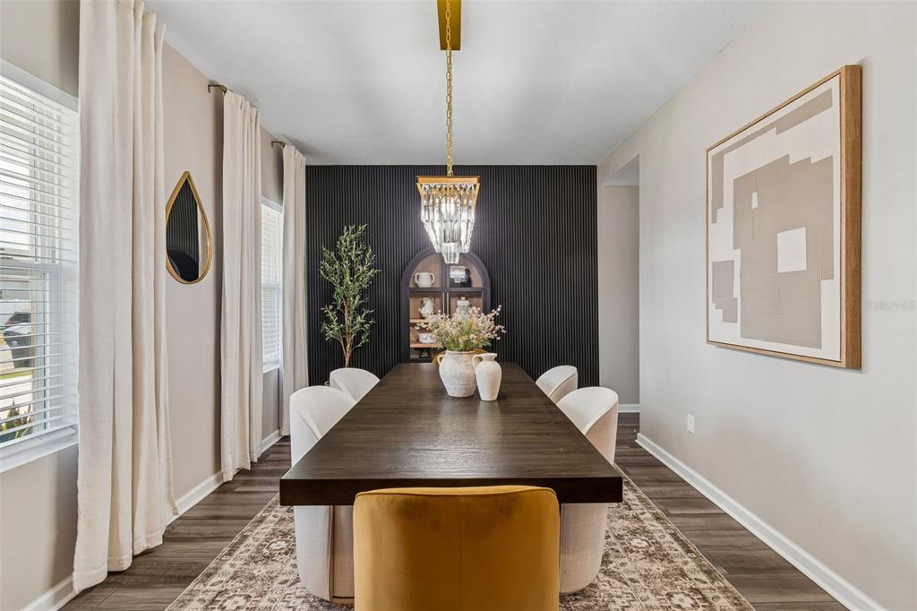 A dining room features a dark wood table, upholstered chairs, and a black slat accent wall — 575 OCEAN SPRAY DRIVE, RUSKIN, FL