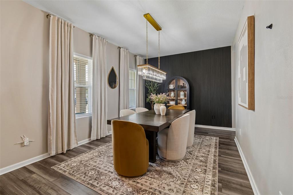 A dining room features a dark wood table, upholstered chairs, and a black slat accent wall — 575 OCEAN SPRAY DRIVE, RUSKIN, FL