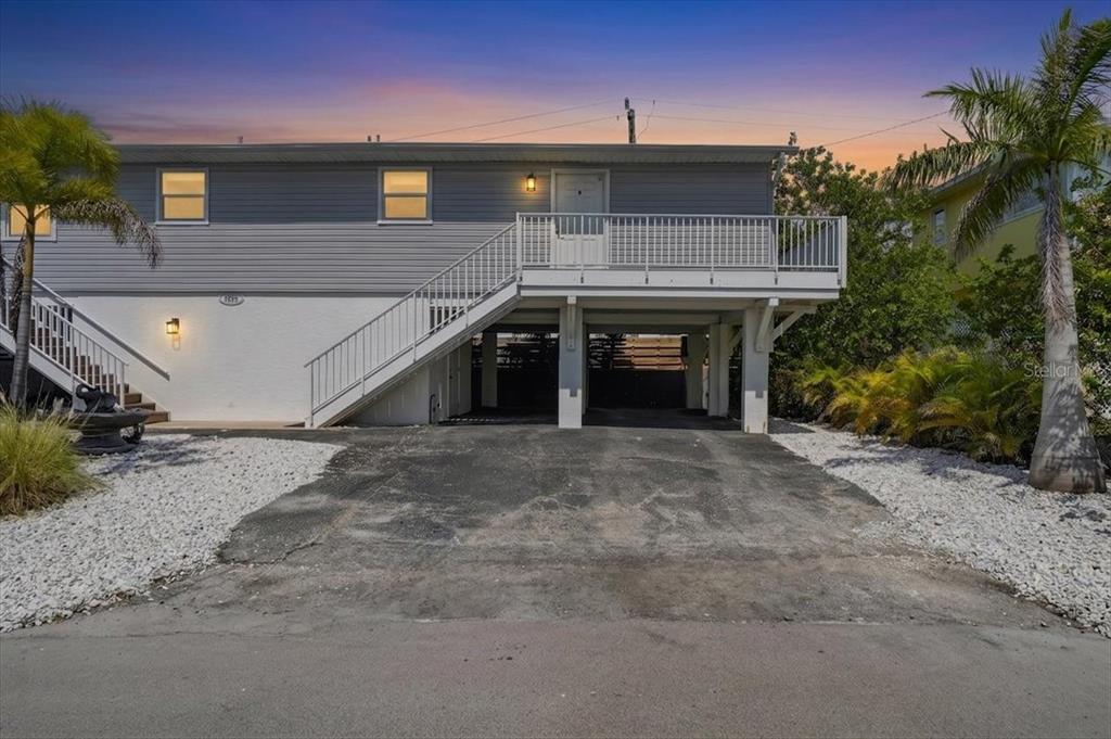 An elevated house with gray siding, a white staircase, and a covered parking area underneath — 3303 6TH AVENUE UNIT B, HOLMES BEACH, FL