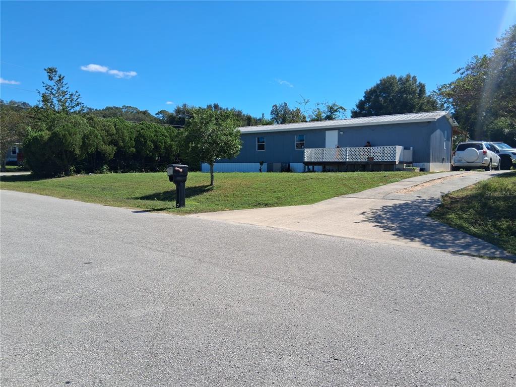 A single-story manufactured home with a white deck sits on a grassy lot — 6290 SE 140TH PLACE, SUMMERFIELD, FL