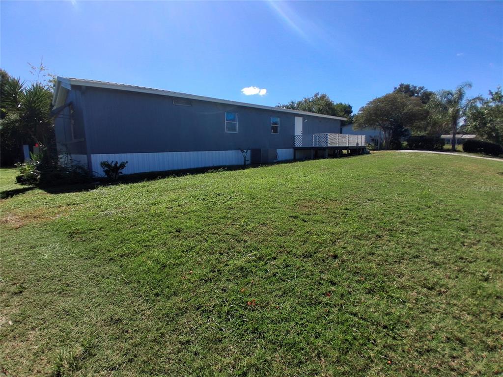 A side view of a manufactured home with a deck and a large grassy yard — 6290 SE 140TH PLACE, SUMMERFIELD, FL