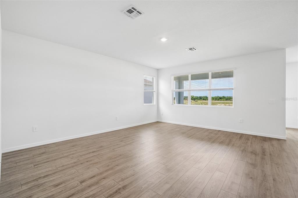 An empty room with white walls, light wood-look flooring, and large windows — 5375 CLOUDBERRY AVENUE, LAKELAND, FL