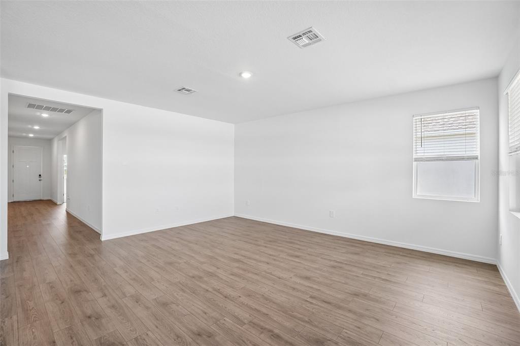 An empty room with light wood-look flooring, white walls, and a single window — 5375 CLOUDBERRY AVENUE, LAKELAND, FL