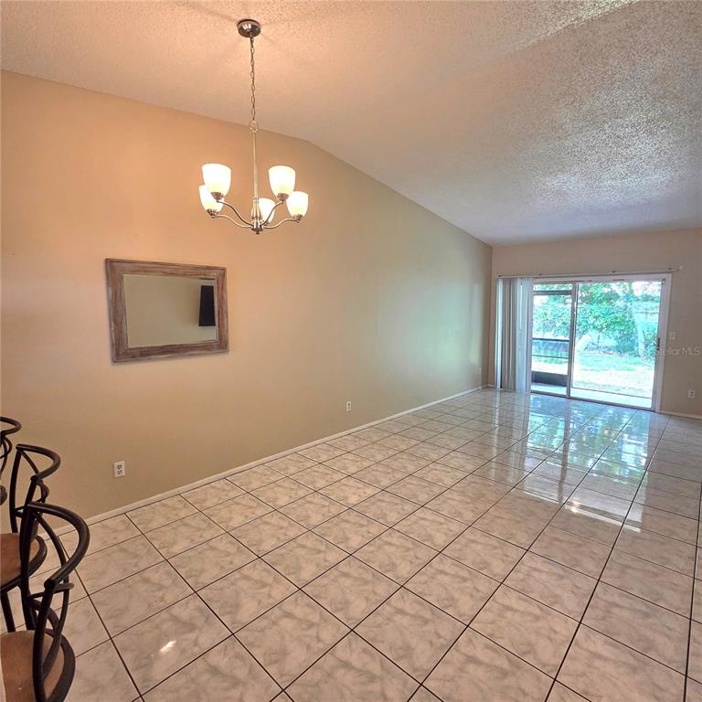 A dining room with beige walls, a chandelier, a mirror, and light-colored tile flooring — 7249 PARKSIDE VILLAS DRIVE N, ST PETERSBURG, FL
