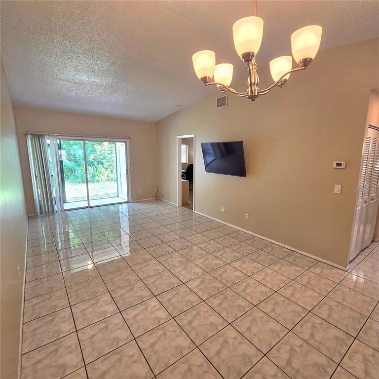 An open living area features light-colored tile flooring, a vaulted ceiling, and a sliding glass door — 7249 PARKSIDE VILLAS DRIVE N, ST PETERSBURG, FL