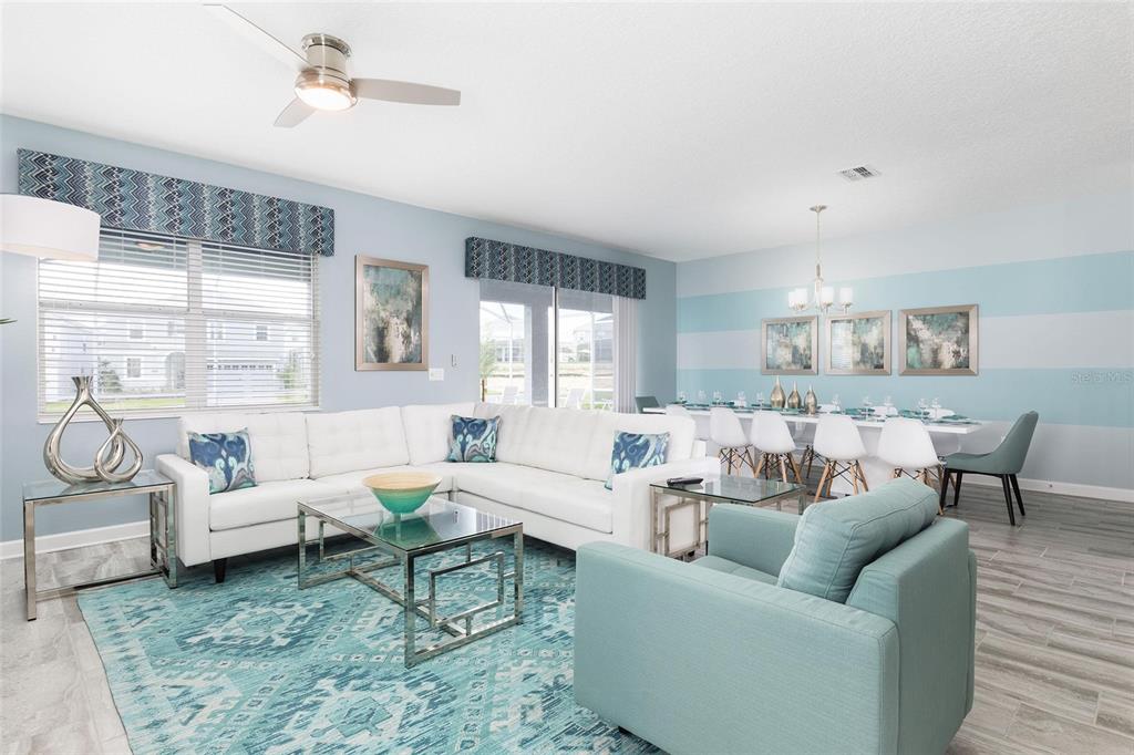 A living and dining room features a white sectional, teal armchair, and blue striped walls — 9045 STINGER DRIVE, DAVENPORT, FL