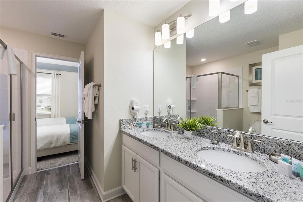 A bathroom features a double vanity with granite countertops, white cabinets, and a large mirror — 9045 STINGER DRIVE, DAVENPORT, FL