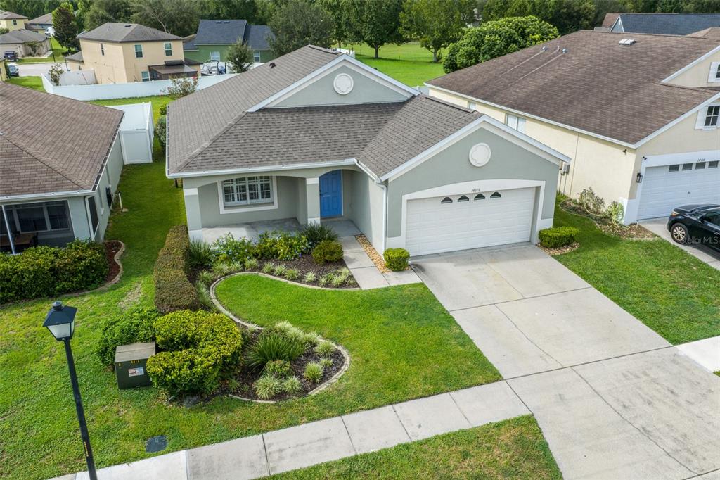 An aerial view of a single-story suburban house with a blue door and two-car garage — 14316 HOLLY HAMMOCK LANE, BROOKSVILLE, FL