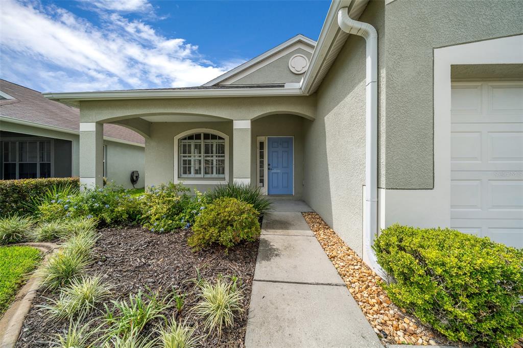 The exterior of a house features a light blue front door and a concrete walkway — 14316 HOLLY HAMMOCK LANE, BROOKSVILLE, FL