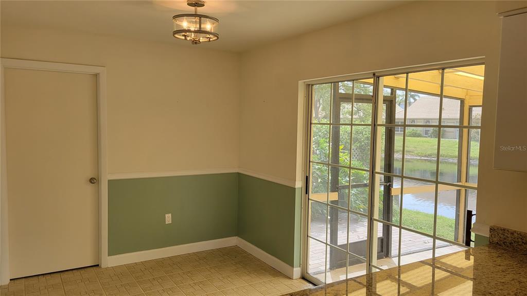 A dining area features sage green wainscoting, tile flooring, a light fixture, and sliding glass doors — 3520 57TH AVENUE CIRCLE W UNIT 10, BRADENTON, FL