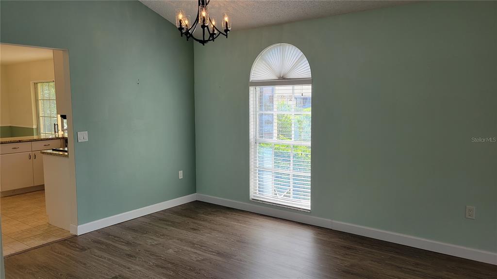 A dining room with light green walls, wood-look flooring, and an arched window — 3520 57TH AVENUE CIRCLE W UNIT 10, BRADENTON, FL