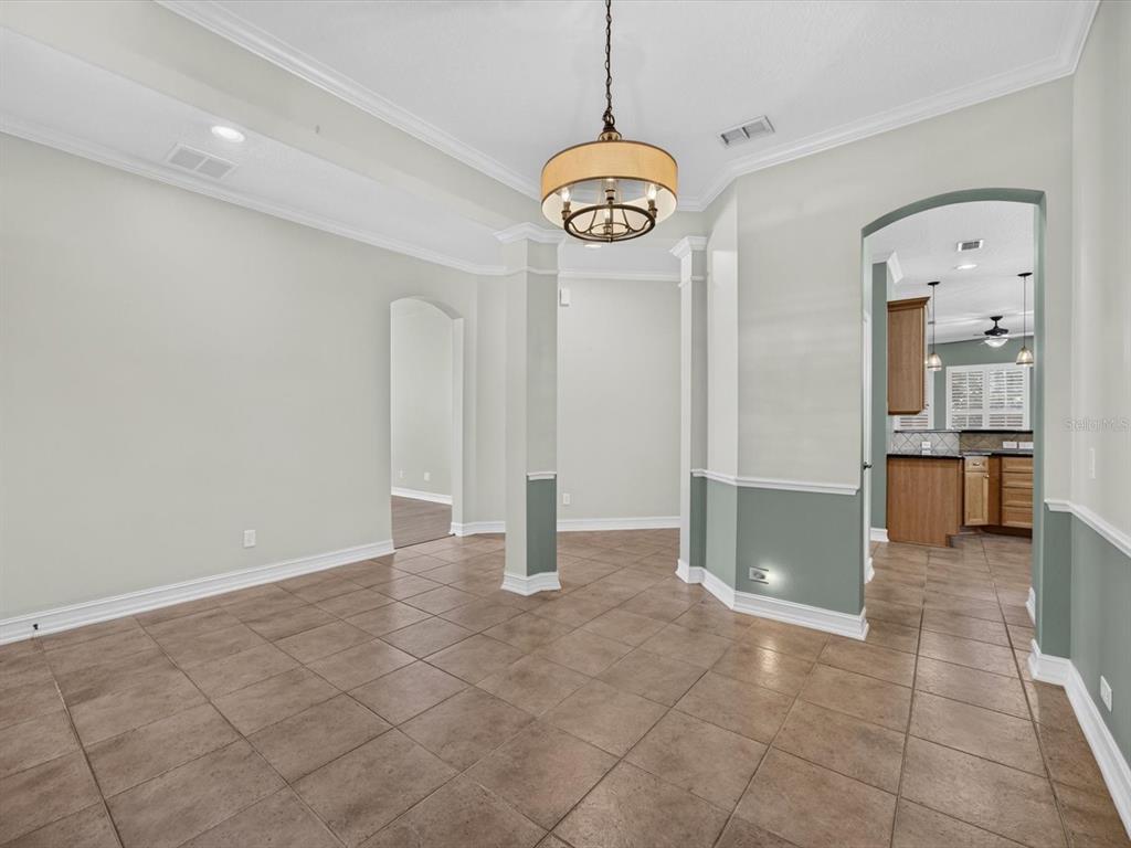 A dining room with tile flooring, a chandelier, and a view into the kitchen — 112 BEDFORD COURT, DELAND, FL