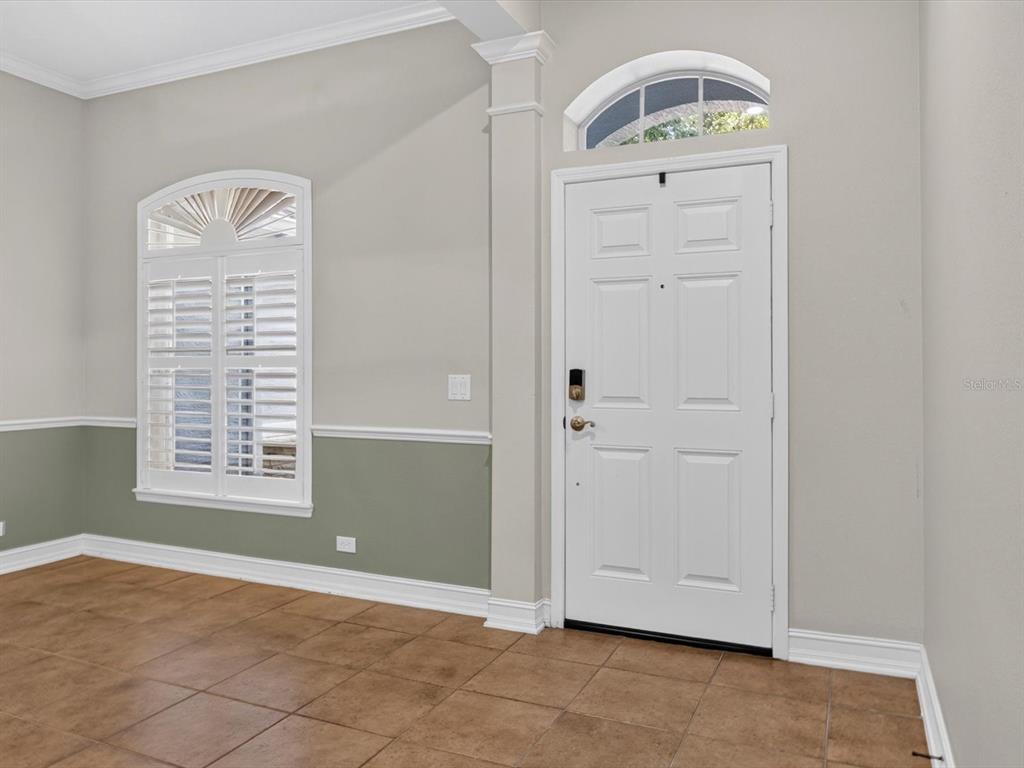 An entryway features tile flooring, a white front door with a transom window, and wainscoting — 112 BEDFORD COURT, DELAND, FL