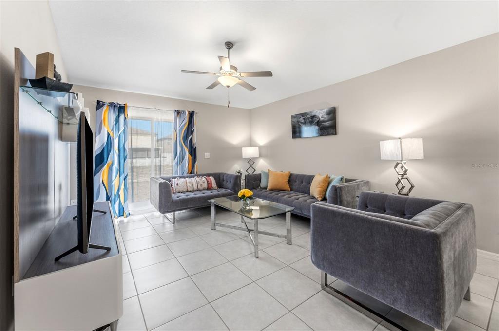 A living room features gray tufted furniture, a glass coffee table, and tile flooring — 343 ARGYLL DRIVE, SPRING HILL, FL