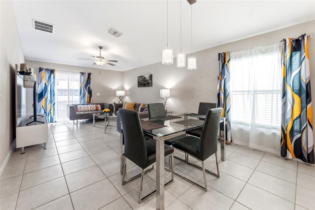 A dining area with a glass table and chairs sits in front of a living room — 343 ARGYLL DRIVE, SPRING HILL, FL