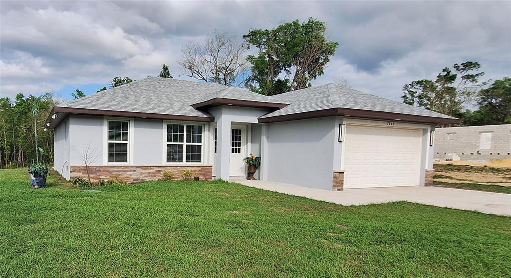 A single-story house with a gray exterior, stone accents, and a two-car garage — 7242 ELAINE DRIVE, WEBSTER, FL