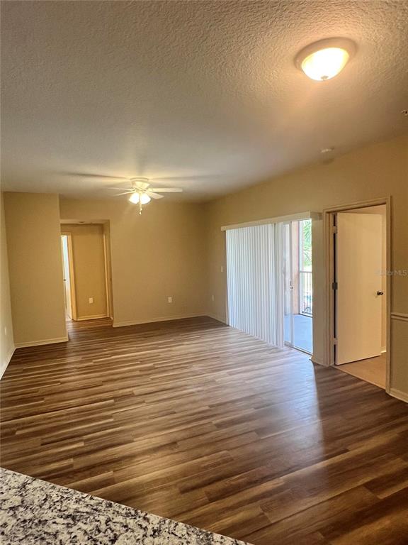 An open living area features wood-look flooring, a ceiling fan, and a sliding glass door — 5512 METROWEST BOULEVARD UNIT 12-201, ORLANDO, FL
