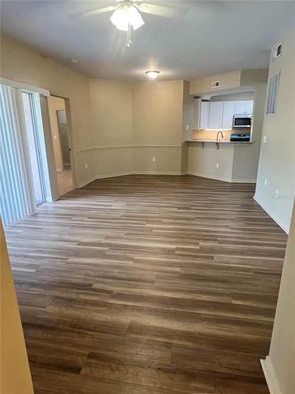An open-concept living and dining area features wood-look flooring and an adjacent kitchen with white cabinets — 5512 METROWEST BOULEVARD UNIT 12-201, ORLANDO, FL