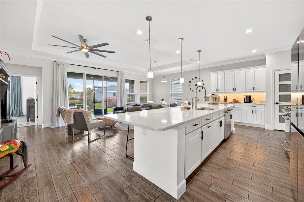 A modern kitchen features a large white island, white cabinetry, and wood-look tile flooring — 5608 NW 39TH LANE, OCALA, FL