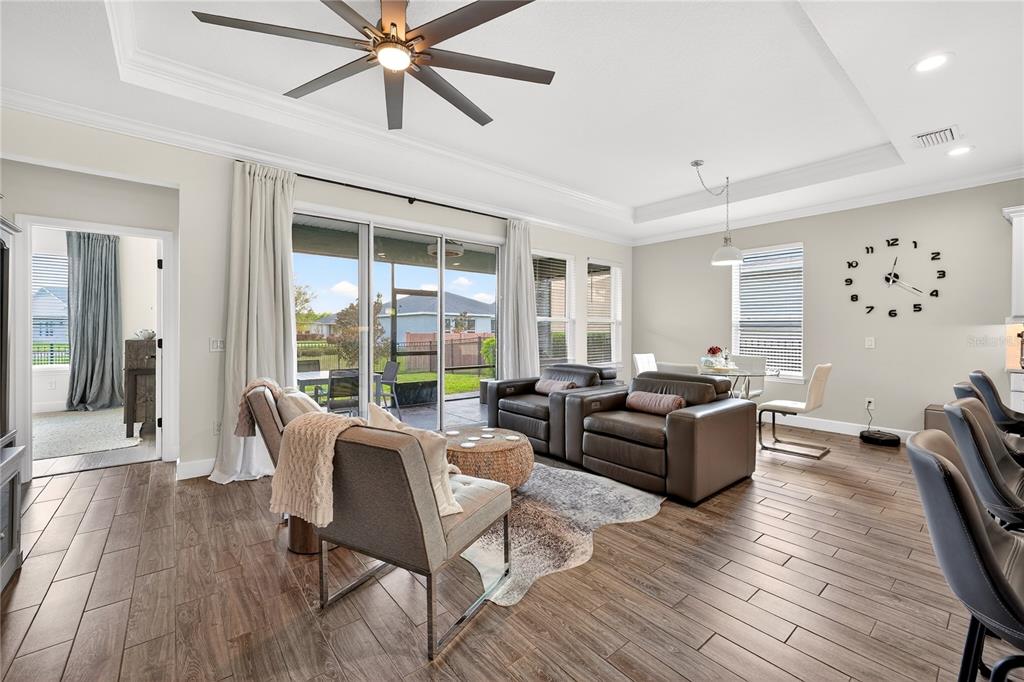 A living room with wood-look tile floors, leather furniture, and a sliding glass door — 5608 NW 39TH LANE, OCALA, FL